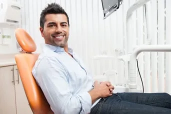 man smiling sitting in dental office chair for exam and dental cleaning Rockaway, NJ & East Hanover, NJ