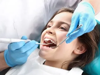 young girl with mouth open and dentist's hands and tools performing dental work, pediatric dentistry Baytown, TX dentist