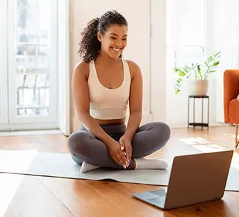 woman on yoga mat with laptop