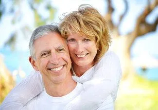 man and woman embracing each other outdoors, smiling with dental implants Fond du Lac, WI
