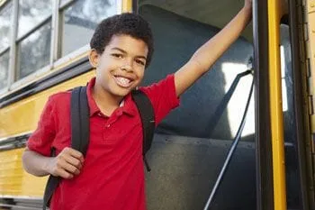 smiling boy getting on school bus