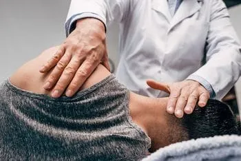 chiropractor in white coat massaging neck of man for spinal adjustment using Memorial Healthcare System health coverage