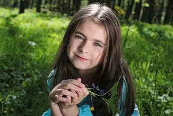 Girl in the Grass with a Flower - Pediatric Dentist and Orthodontics in Chicopee, Springfield and Ludlow, MA