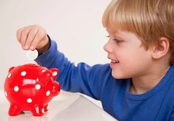 boy inserting money in piggy bank from using Florida Healthy Kids Health Plan with stumpff chiropractor