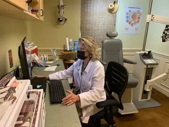 Dr. Lander at her desk, wearing a mask.