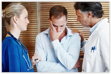 Image of patient being consoled by doctor and nurse