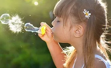 Girl blowing on a flower - Pediatric Dentist in Vermont and New Hampshire