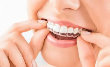 hand holding clear teeth aligners in mouth, Invisalign Baytown, TX 