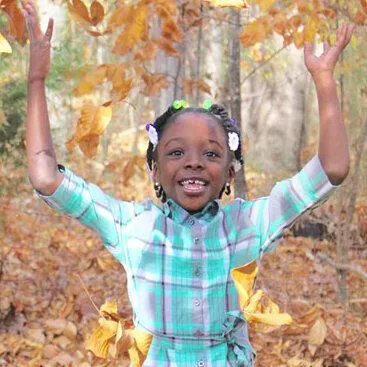 Child playing in pile leaves