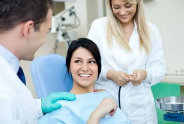 teen girl in dentist chair smiling talking with male dentist and assistant, general dentist Salem, OR