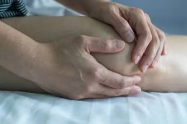 Man holding his knee feeling of intense pain caused by Bursitis.
