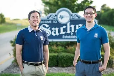Dr. Tony Nguyen and Dr. Brian Davila outside with Sachse, TX town sign, dentists in Sachse, TX