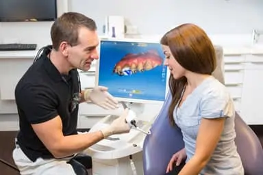 dentist showing female patient CEREC machine with her teeth images on screen, same day CEREC crowns Peachtree City, GA