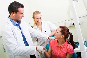 redhead woman in dental exam room, shaking hands with male dentist Salem, OR root canal treatment
