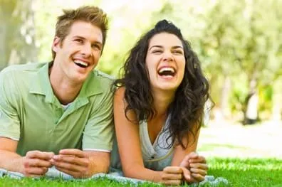man lying in grass next to woman, both smiling nice teeth, Teeth Whitening Melrose, MA dentist