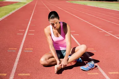 Women sitting on the running field because of foot injury