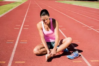 Women sitting on the running field because of foot injury