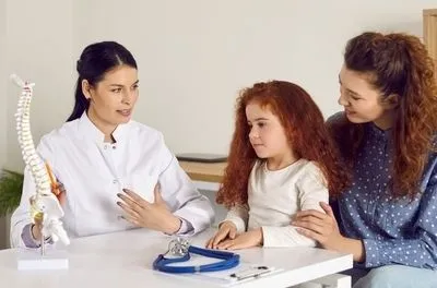 Doctor and patient on clinic with looking in spine model.