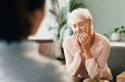 Woman feeling anxious talking to therapy indoor.