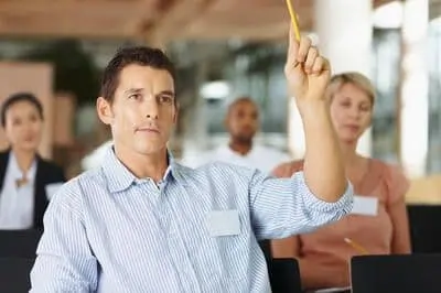 man sitting in class, raising his hand