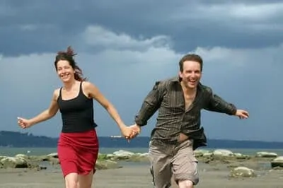 couple holding hands and running on beach