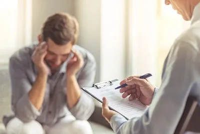 Therapist providing emotional support to a male client during depression treatment session