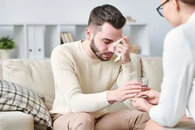 Man expressing deep sorrow while receiving grief counseling support