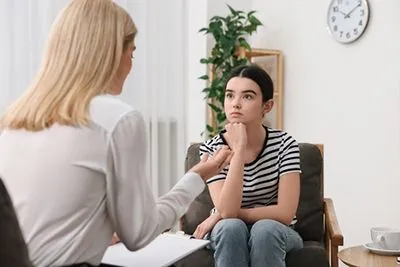Adolescent girl receiving mental health support during a therapy appointment.