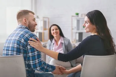 Couple sitting together in a therapy session, discussing their relationship with a counselor.