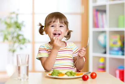 Smiling young girl eating salad