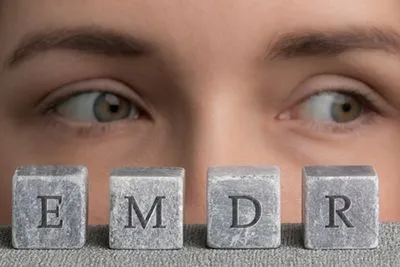 Close-up of woman’s face with eyes looking left and stone cubes labeled EMDR