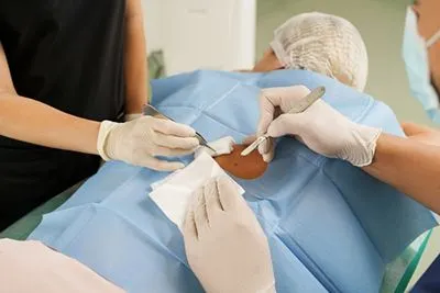 Dermatologist and medical assistant performing surgical removal of skin cancer.