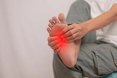 Man clutching his foot in discomfort due to pain