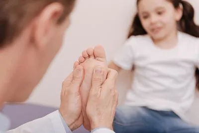 Doctor checking the condition of foot in a young girl