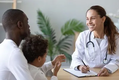 Doctor talking to a little boy with his father.