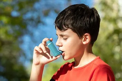 Young boy using asthma inhaler in an outdoor setting