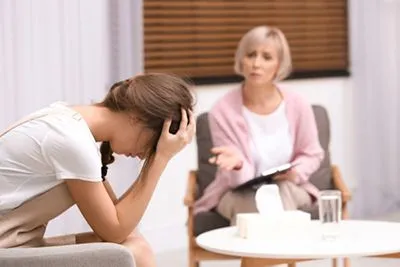 Woman feeling depressed with the therapist on the background