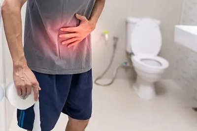 Man suffering from diarrhea holding tissues in a bathroom