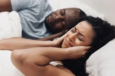 woman disturb by her husband while snoring