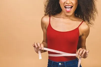 Happy woman proudly showing her weight loss progress after healthy lifestyle changes