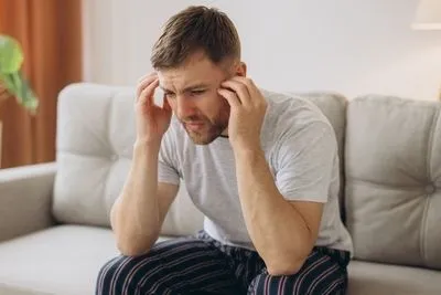 Man feeling confused and mad while sitting on sofa