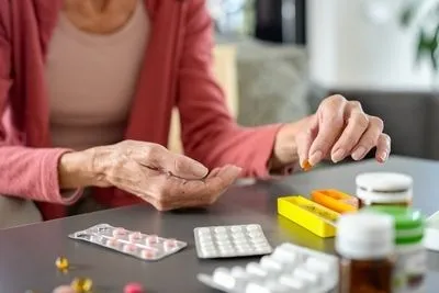 Senior woman with a lot of maintenance medicine on table