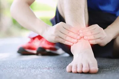 Male jogger clutching his injured ankle