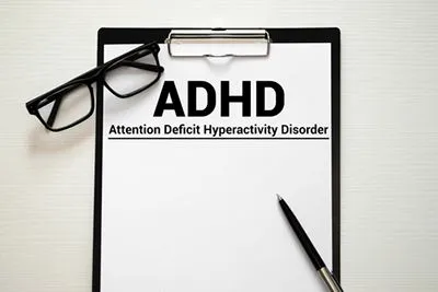 Close-up of clipboard with ADHD written on document and pen next to it