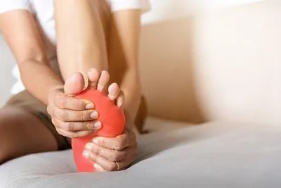 Woman holding her foot in discomfort due to neuropathy and numbness
