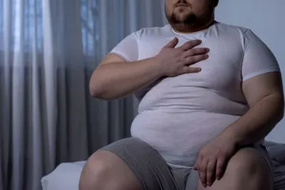 Obese man holding his chest in pain