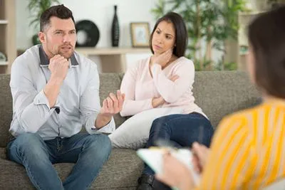 Separated couple discussing parenting strategies in therapy session.