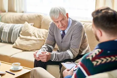 Elderly man expressing sorrow during a grief counseling session.