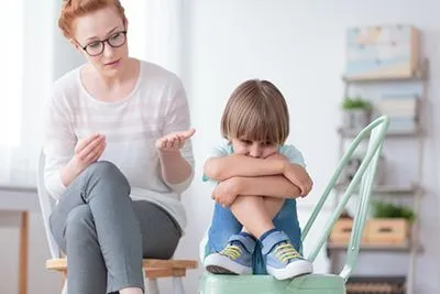 Therapist talking to a young boy facing back to her