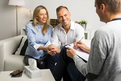 Happy couple talking with a male therapist during a counseling session